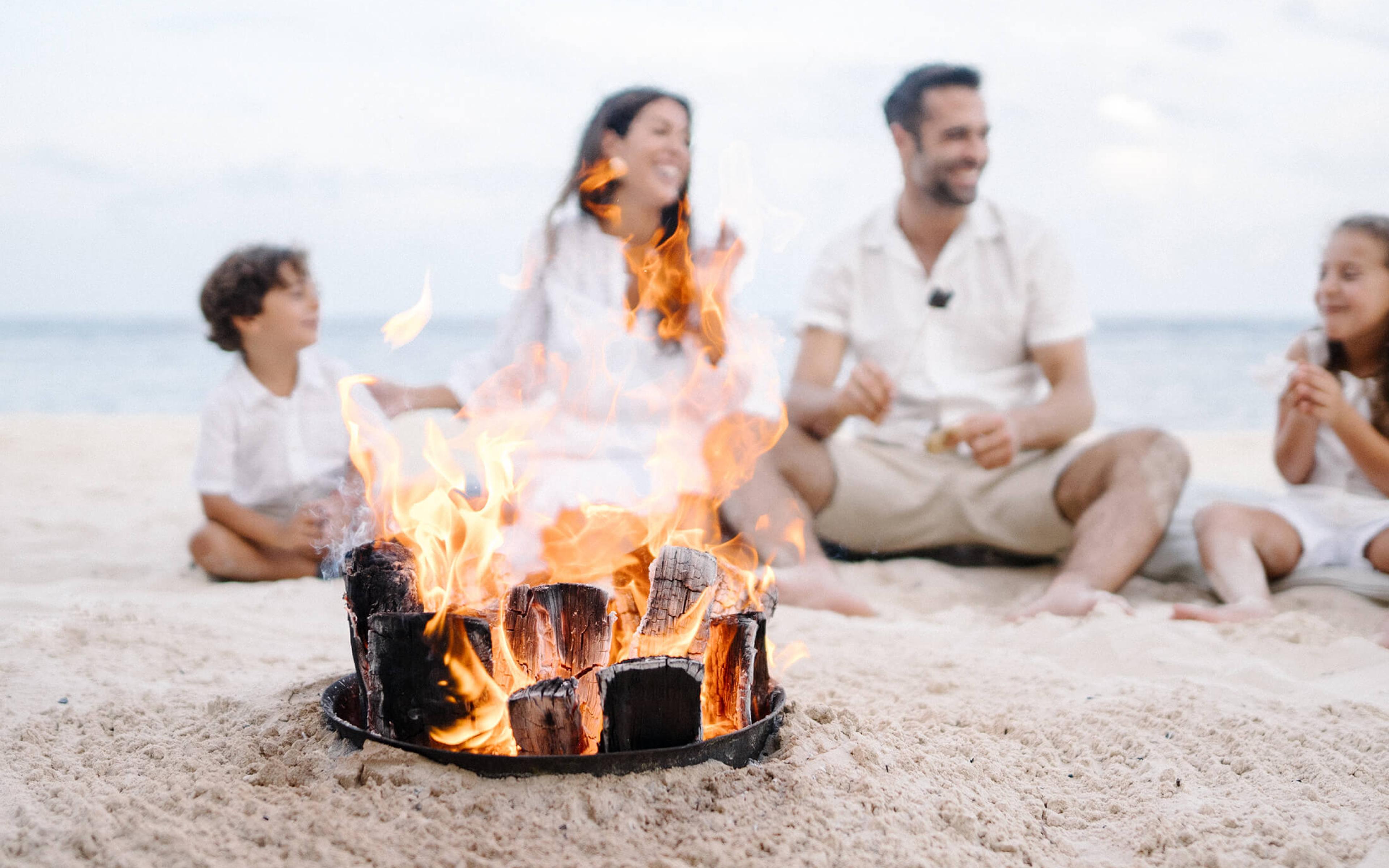 beach bonfire with a family sitting by it