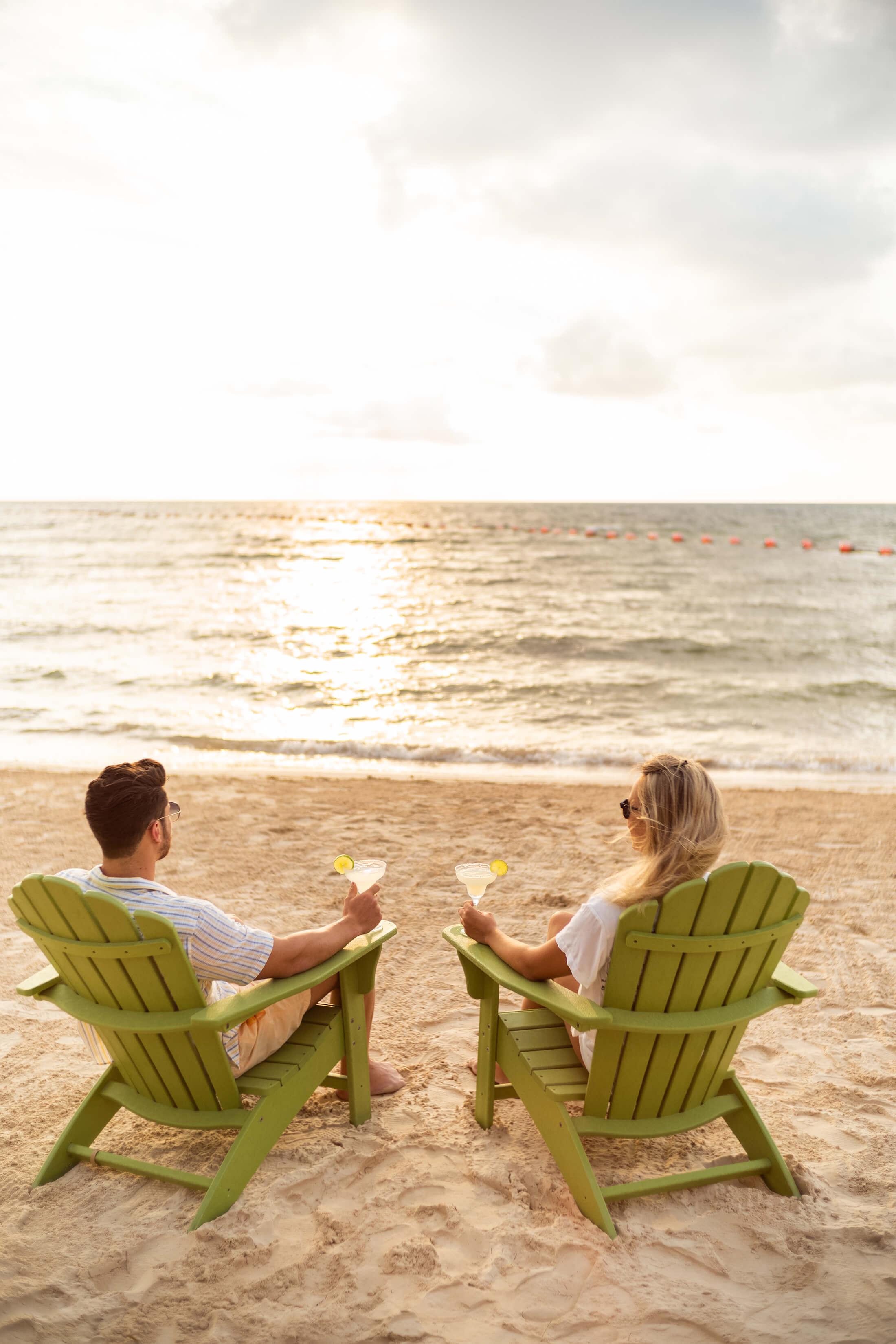 A couple enjoys margaritas while watching the sunset on the beach