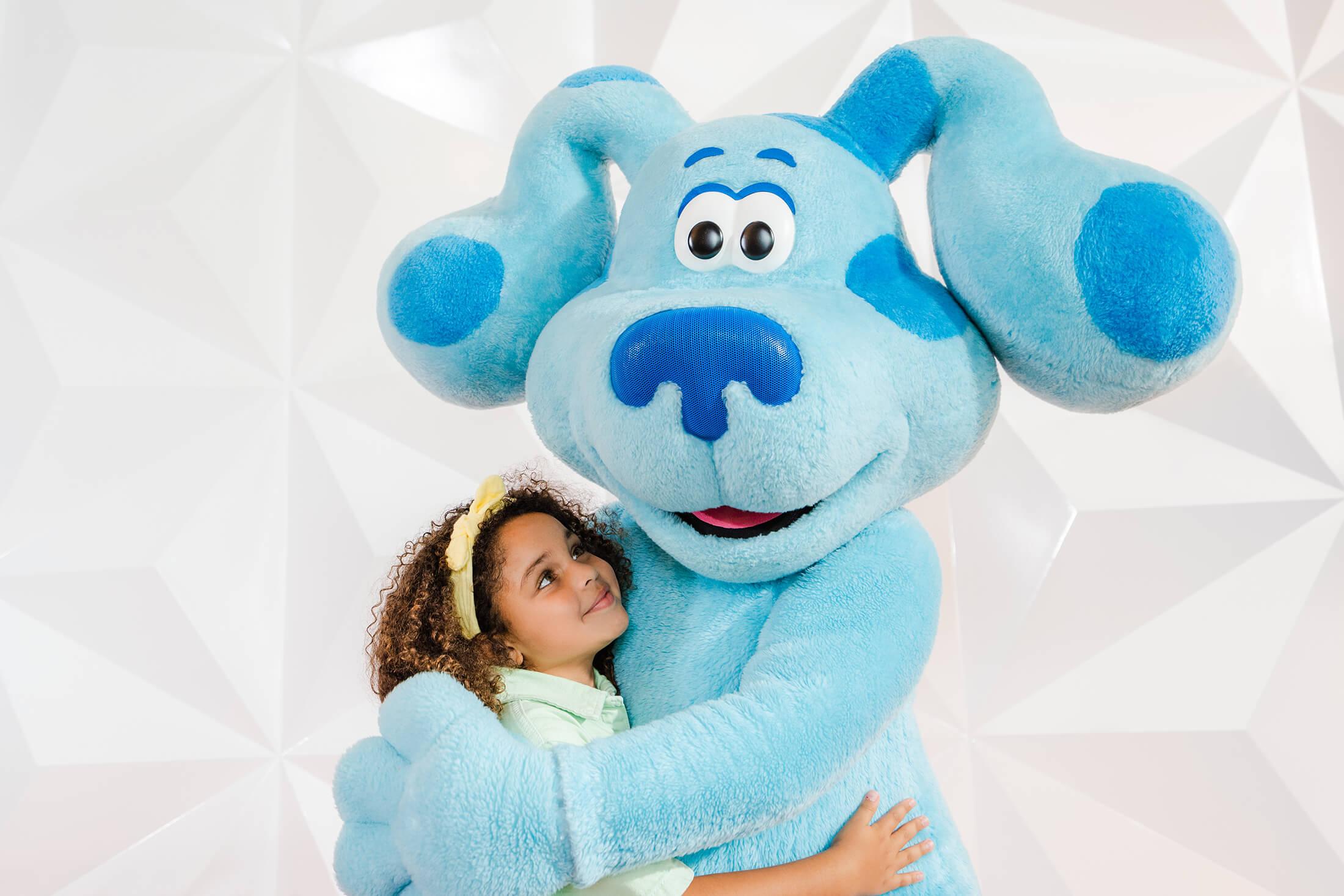 A toddler snuggles with a Blue mascot