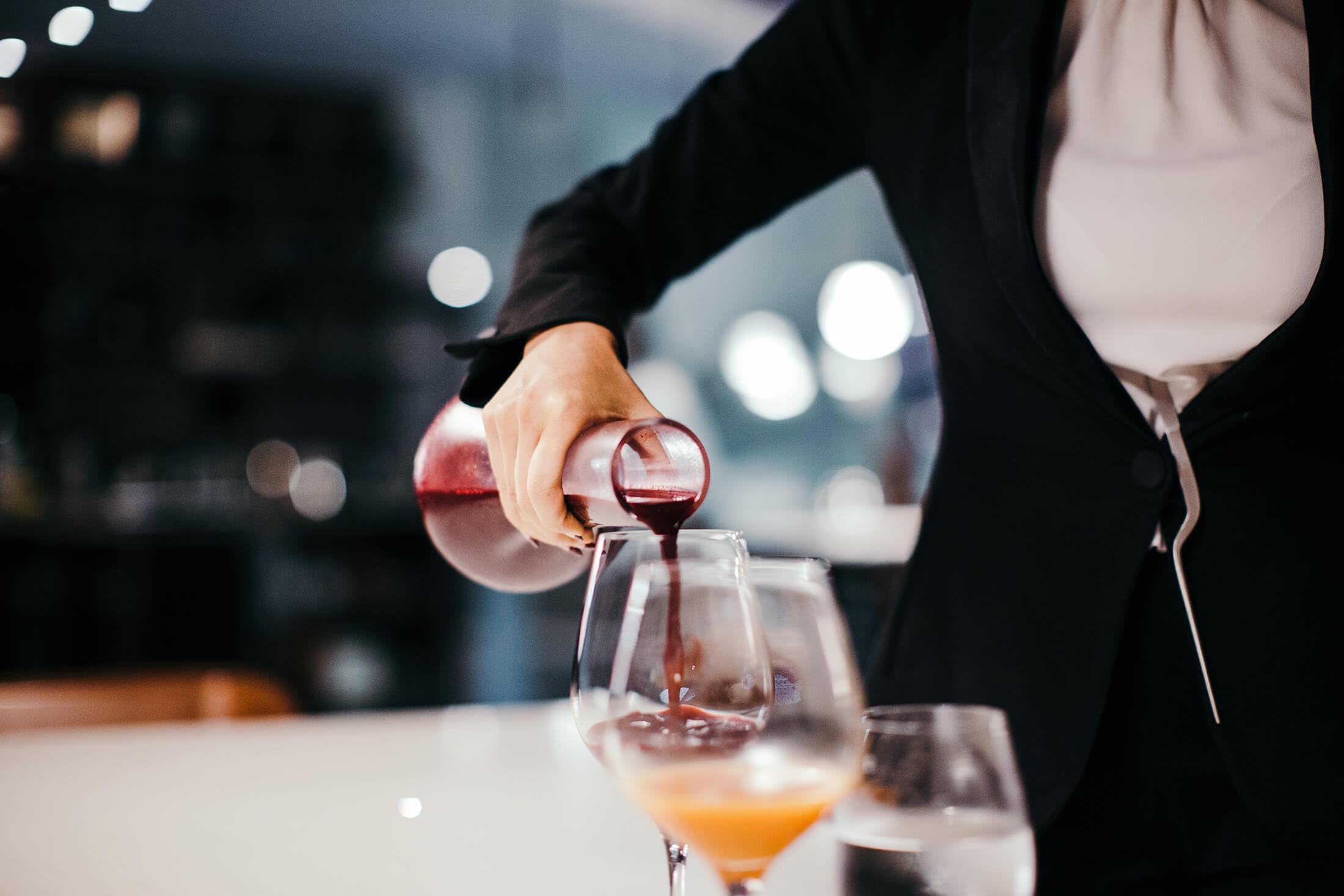 a person pouring wine into a glass