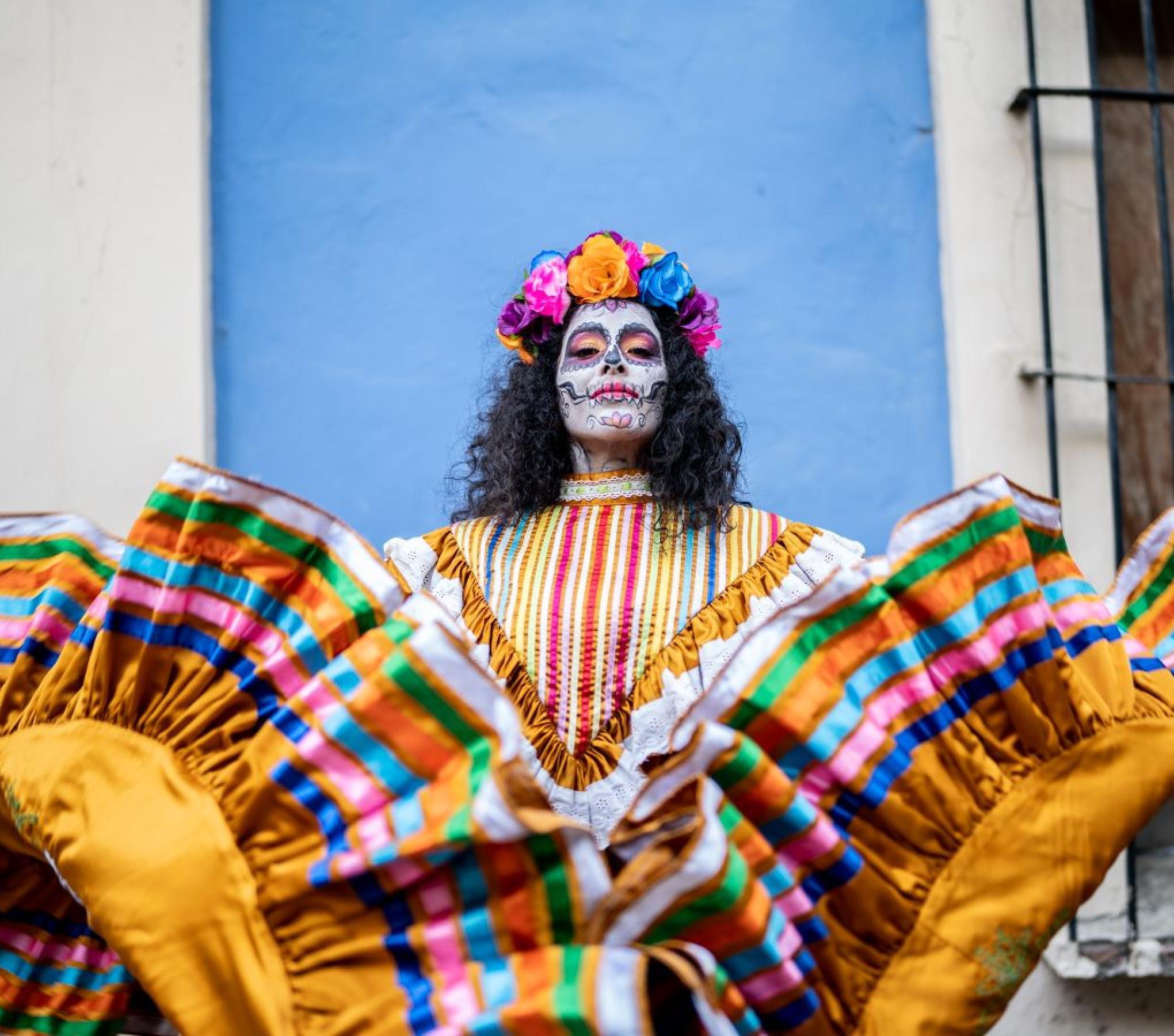 A woman with a traditional mexican dress and a catrina face painting