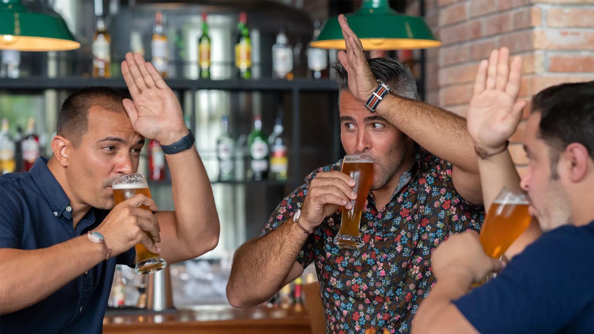 Three people drinking beers at a bar