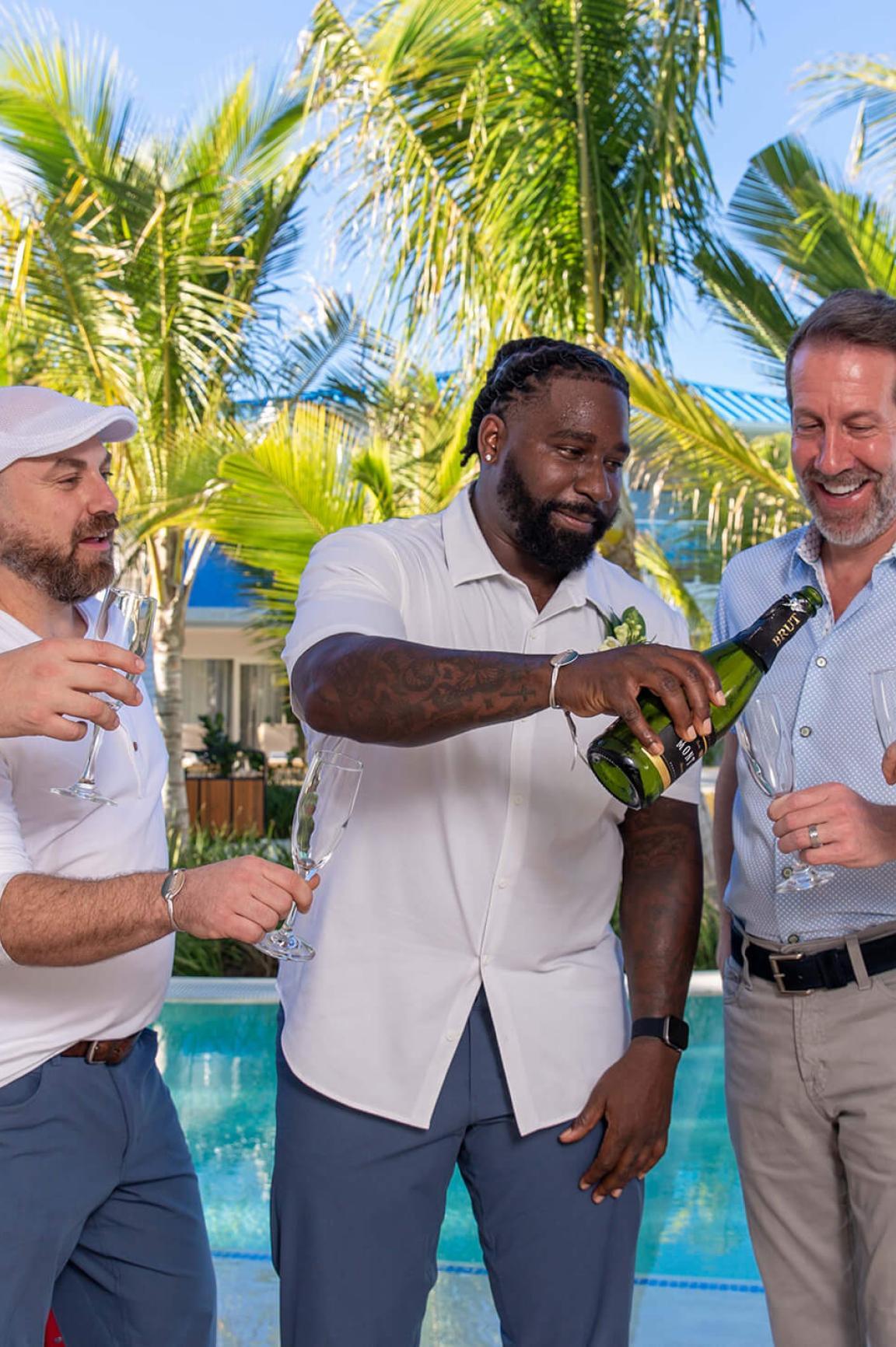 A group of men toast champagne by the pool