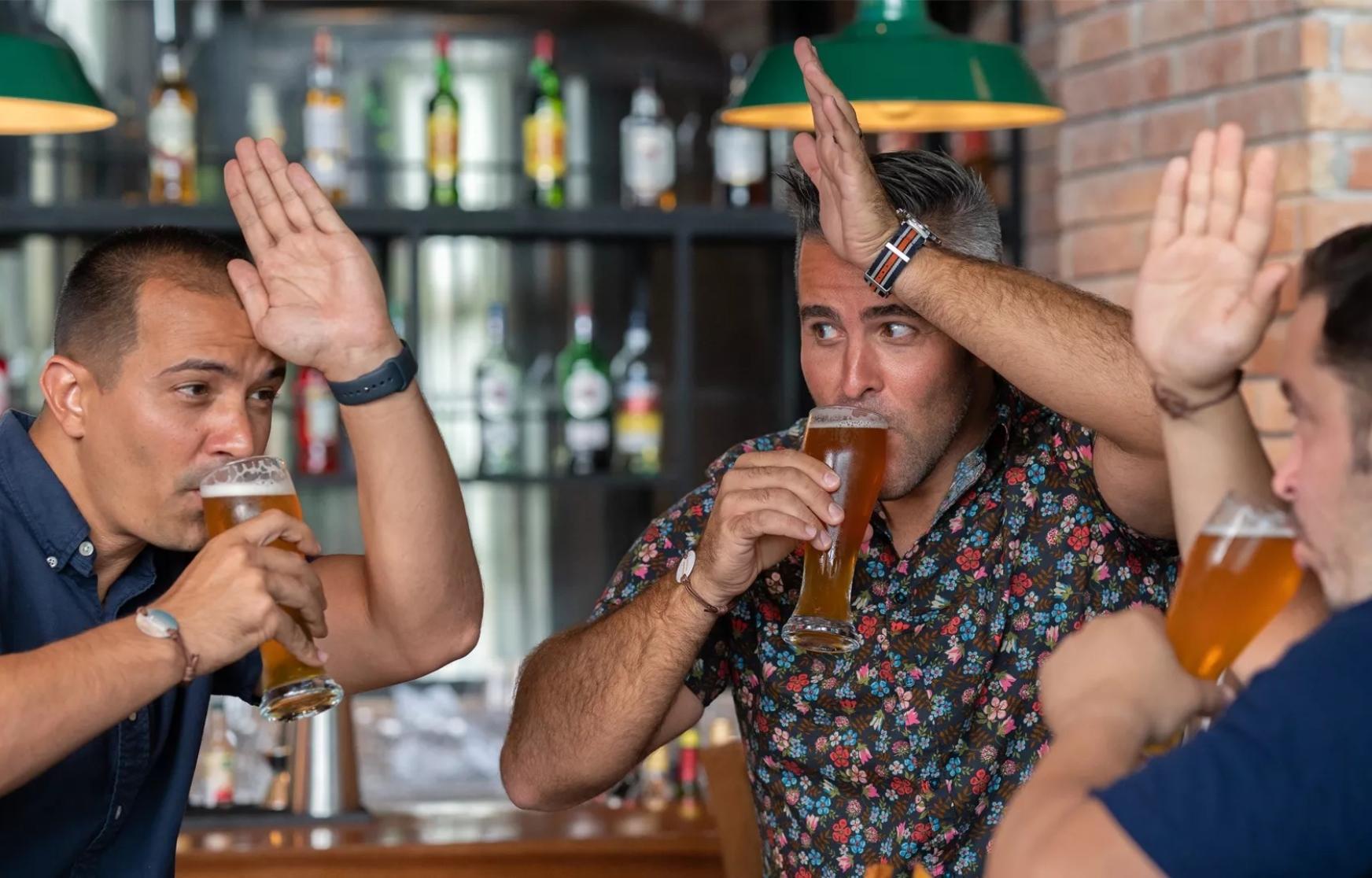 Three people drinking beers at a bar